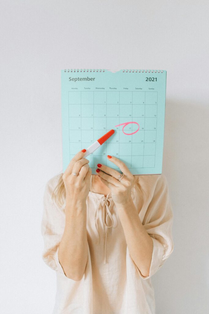 Woman holding a calendar with a date circled, conveying anticipation or planning.